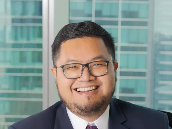 Portrait of Adiyatma Ramadhan, Director, Indonesia, with city landscape featuring building with lots of windows in the background.