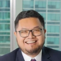 Portrait of Adiyatma Ramadhan, Director, Indonesia, with city landscape featuring building with lots of windows in the background.