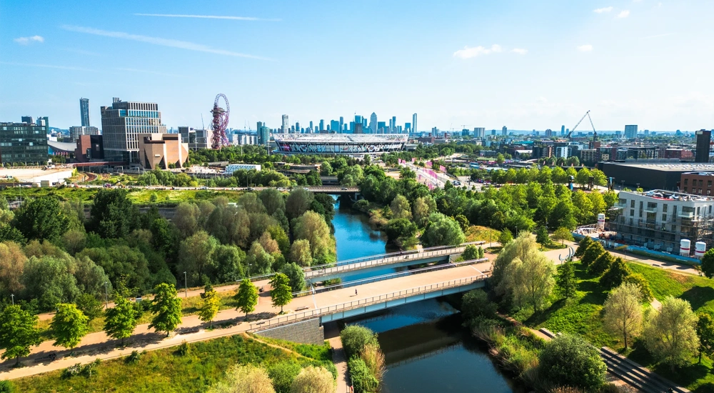 Aerial view, taken by drone, depicting the modern architecture of Stratford in East London. In the foreground is Stratford wetlands on the River Lea, while the skyline is dominated by Queen Elizabeth Olympic Park and London Stadium, home of West Ham United FC. The high rise towers of the Isle of Dogs, including Canary Wharf, are visible on the horizon.