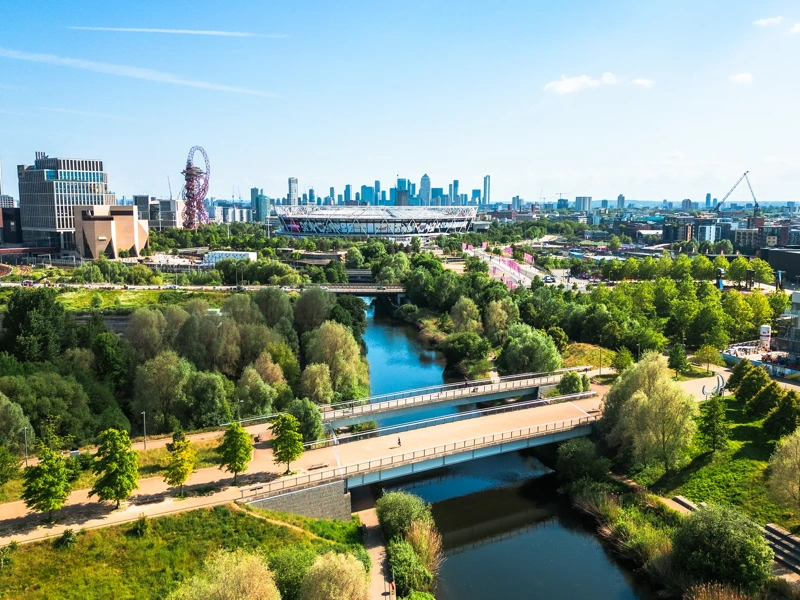Aerial view, taken by drone, depicting the modern architecture of Stratford in East London. In the foreground is Stratford wetlands on the River Lea, while the skyline is dominated by Queen Elizabeth Olympic Park and London Stadium, home of West Ham United FC. The high rise towers of the Isle of Dogs, including Canary Wharf, are visible on the horizon.