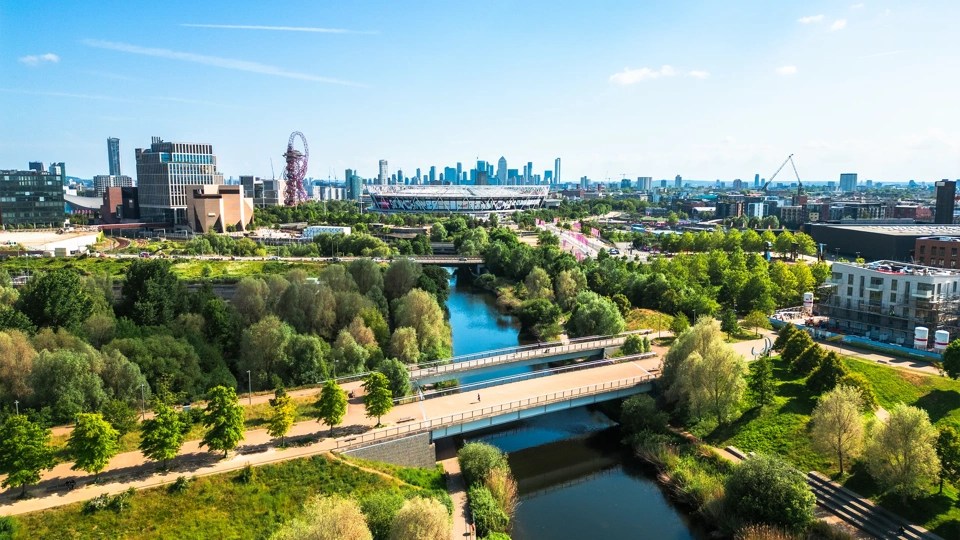 Aerial view, taken by drone, depicting the modern architecture of Stratford in East London. In the foreground is Stratford wetlands on the River Lea, while the skyline is dominated by Queen Elizabeth Olympic Park and London Stadium, home of West Ham United FC. The high rise towers of the Isle of Dogs, including Canary Wharf, are visible on the horizon.
