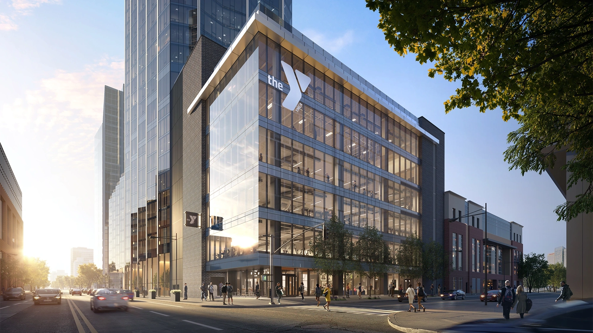 A striking glass building with the YMCA logo and sunset in the background.