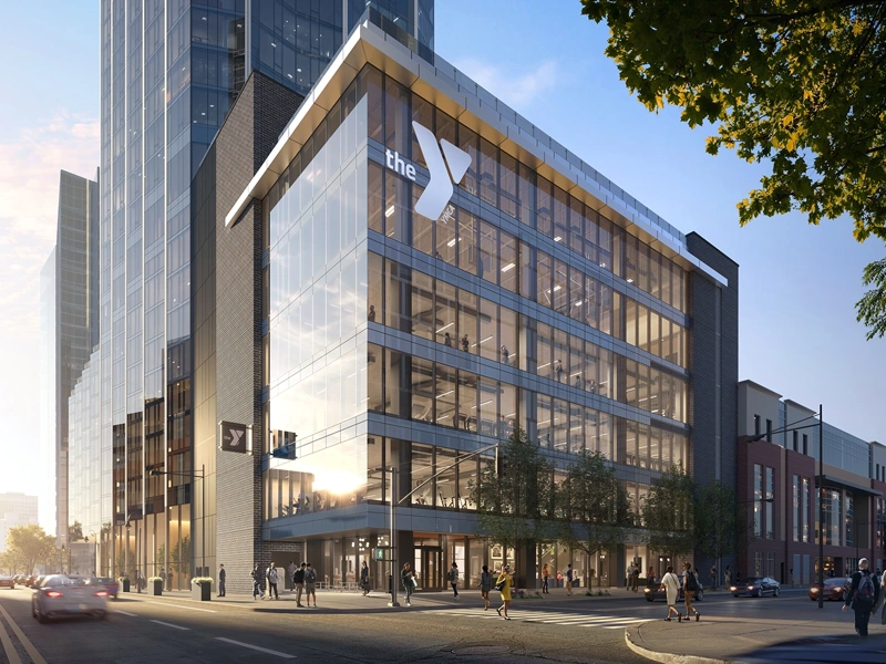 A striking glass building with the YMCA logo and sunset in the background.