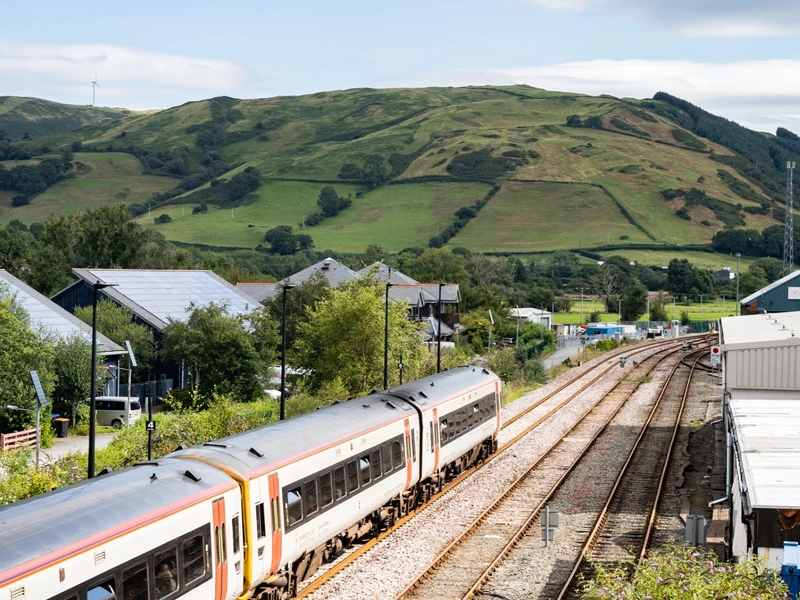 Train in a rural area, with green hill in the background