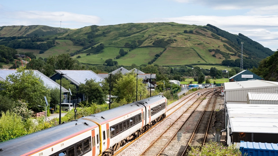 Train in a rural area, with green hill in the background
