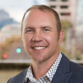 Portrait of Donovan Nolan, standing in office in front of Turner & Townsend sign