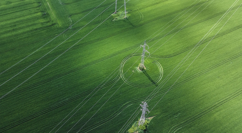 Aerial view of of green field and overhead electricity lines