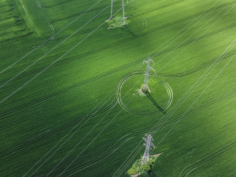 Aerial view of of green field and overhead electricity lines