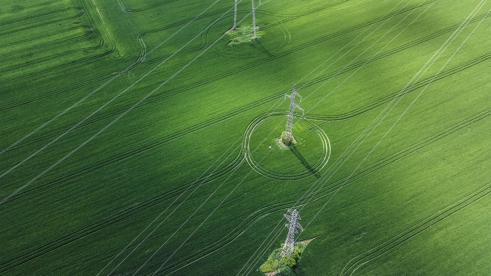 Aerial view of of green field and overhead electricity lines