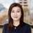 Cheryl Lum, Director, Cost Management, Singapore, outside in front of a blurred brown background featuring a building and mix of natural and urban elements.