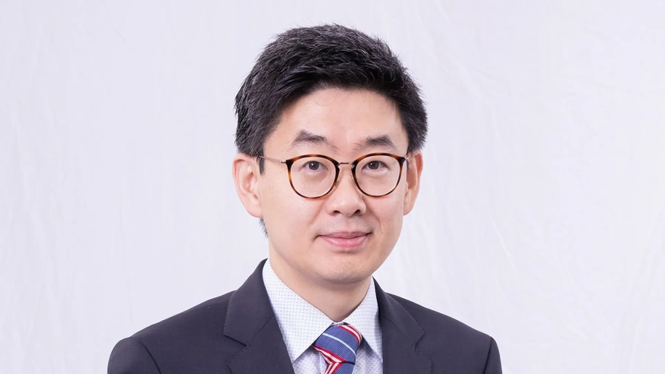 Portrait of Yan Zhou, Director of Energy and Infrastructure, Greater China, smiling in blue suit against white backdrop.