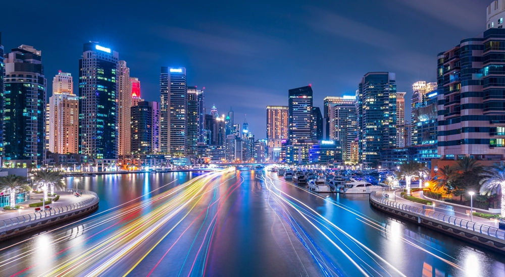 Skyscrapers at night alongside digitally imposed lines of colour on the water