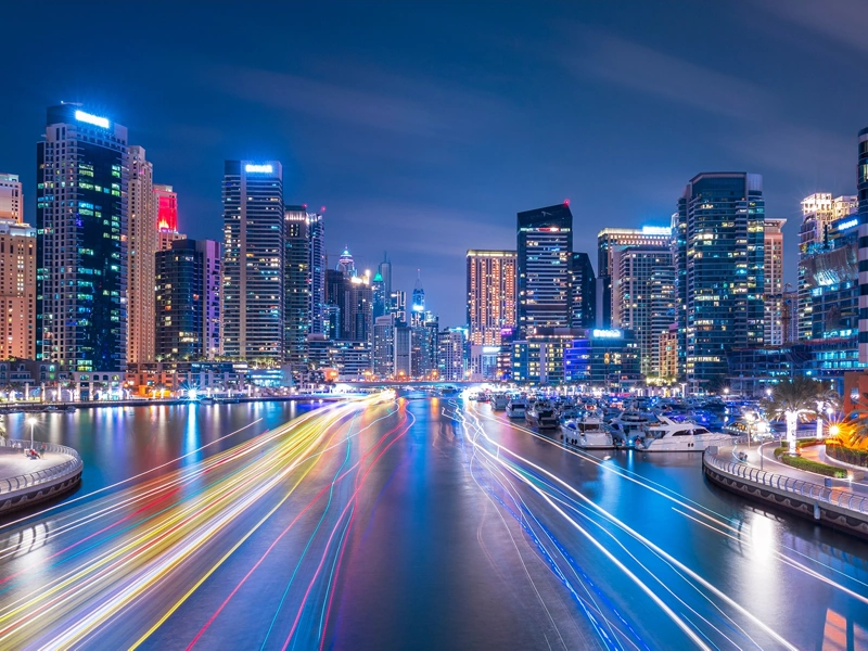 Skyscrapers at night alongside digitally imposed lines of colour on the water