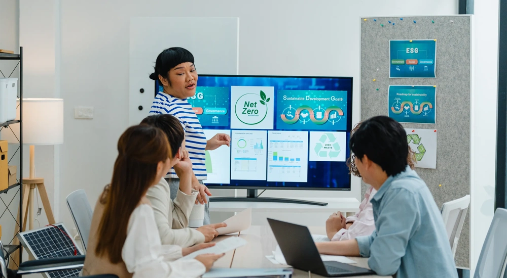 A group of coworkers discuss renewable energy solutions, emphasizing sustainable business practices in a modern office setting.