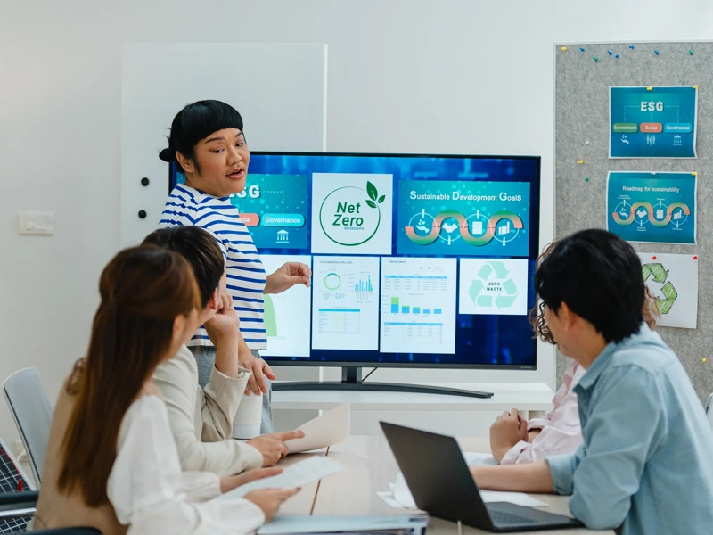 A group of coworkers discuss renewable energy solutions, emphasizing sustainable business practices in a modern office setting.