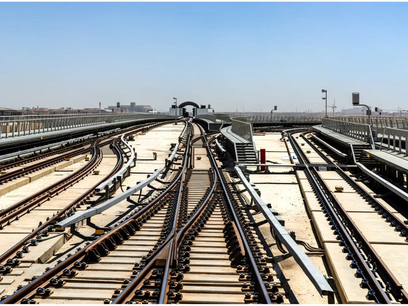 A view of the Riyadh Metro railway tracks and rail switches leading to a maintenance depot under a clear blue sky.