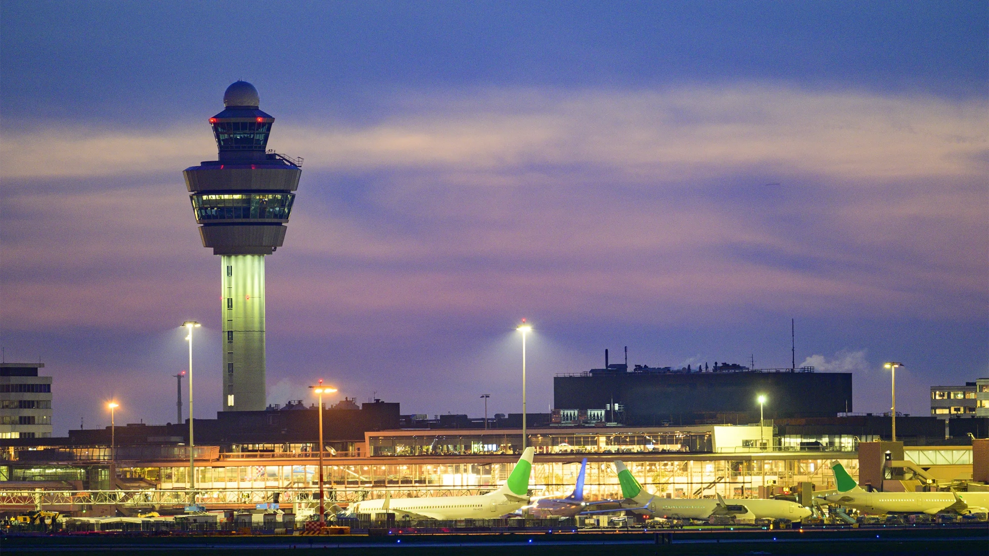 Schipol Airport airfield, terminal and air traffic control tower illuminated at dusk, Amsterdam, The Netherlands