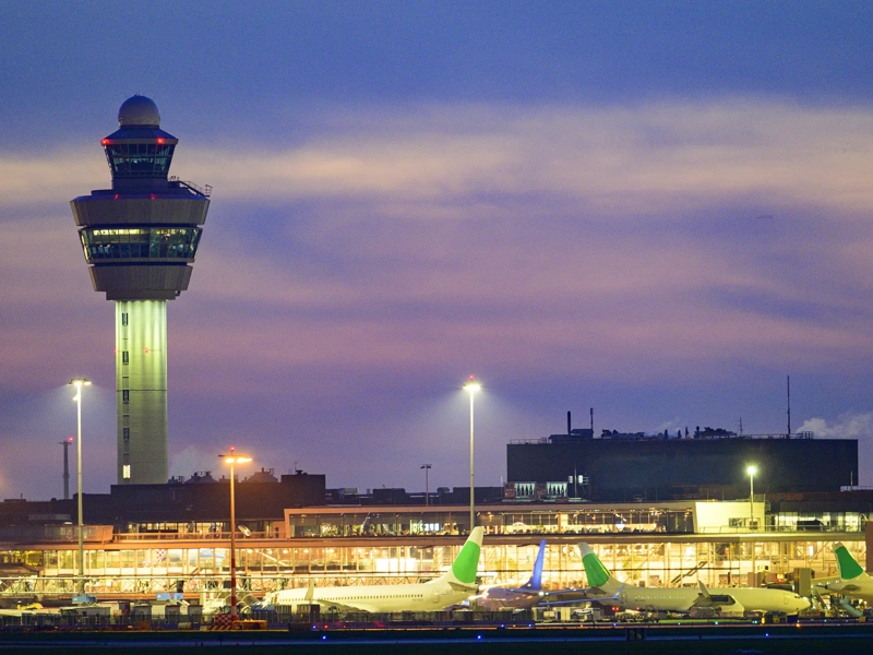 Schiphol airport with various airplanes at night. Schiphol is one of the busiest and largest airports in Europe, located near Amsterdam, Netherlands. It serves as a major hub for international flights and is a key gateway to Europe.