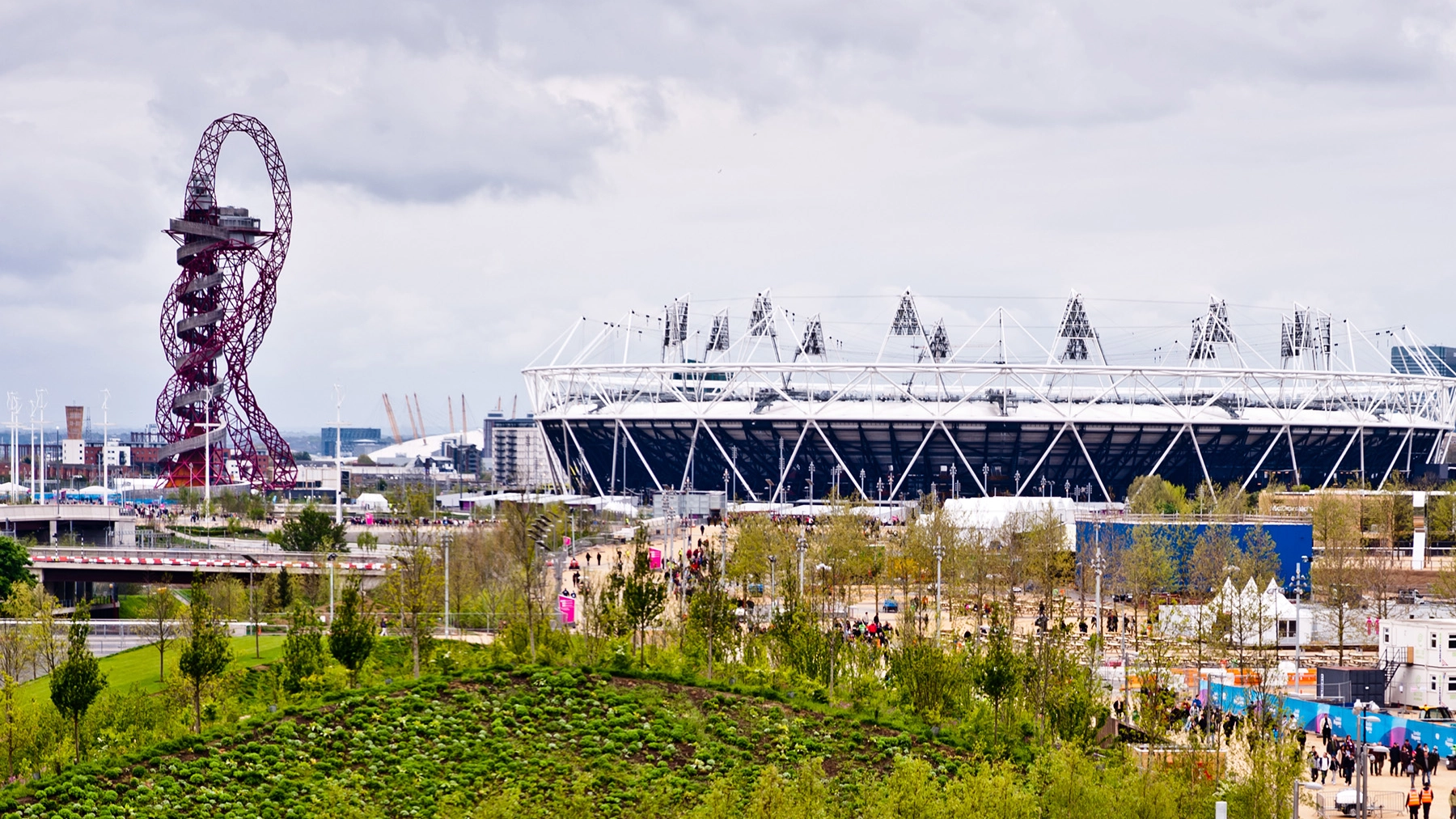 Sports stadium exterior surrounded by fun fair and rollercoaster 