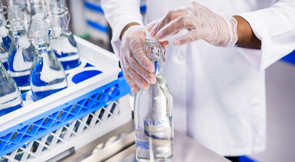 Factory worker in white lab coat bottling water