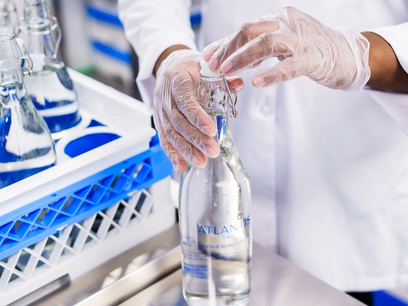 Factory worker in white lab coat bottling water
