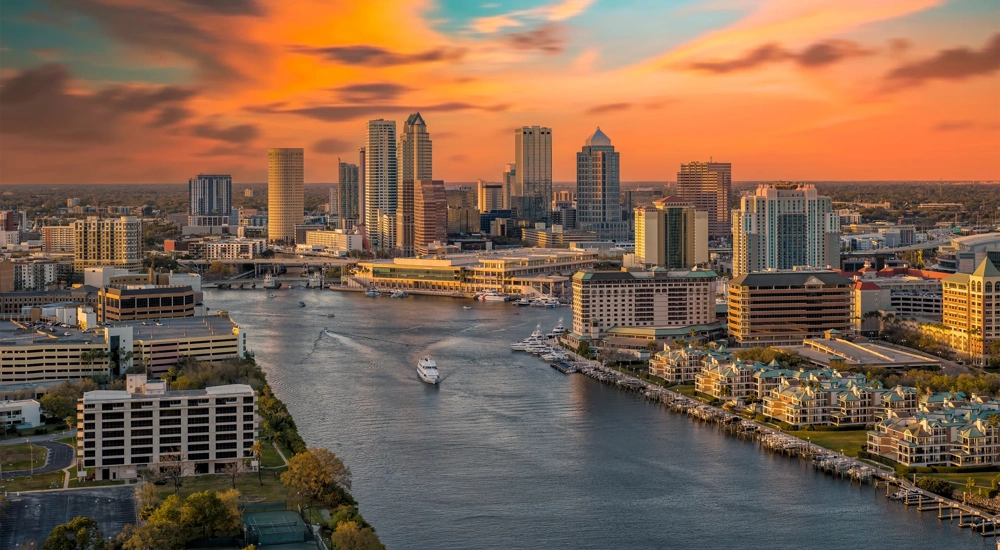 Ariel view of city skyline at sunset with boats on river.