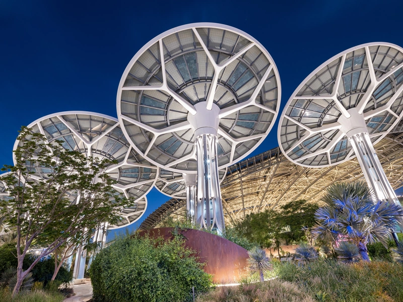 Multiple mushroom shaped solar panels against dark blue sky