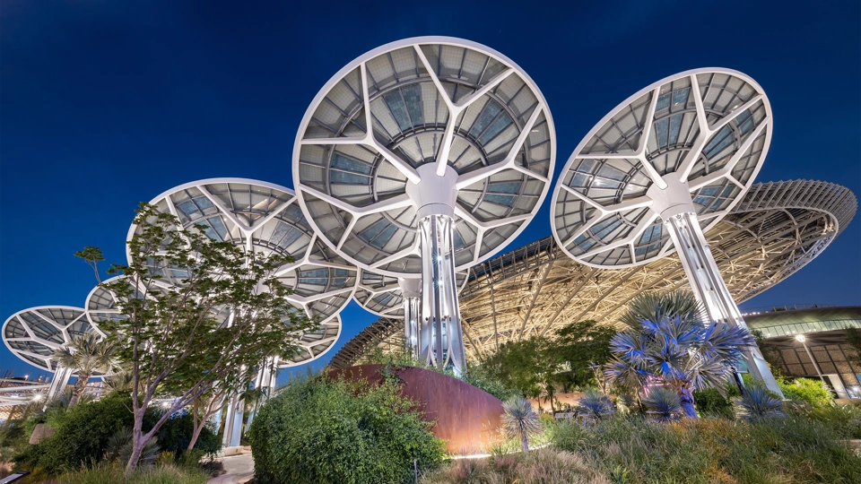 Multiple mushroom shaped solar panels against dark blue sky