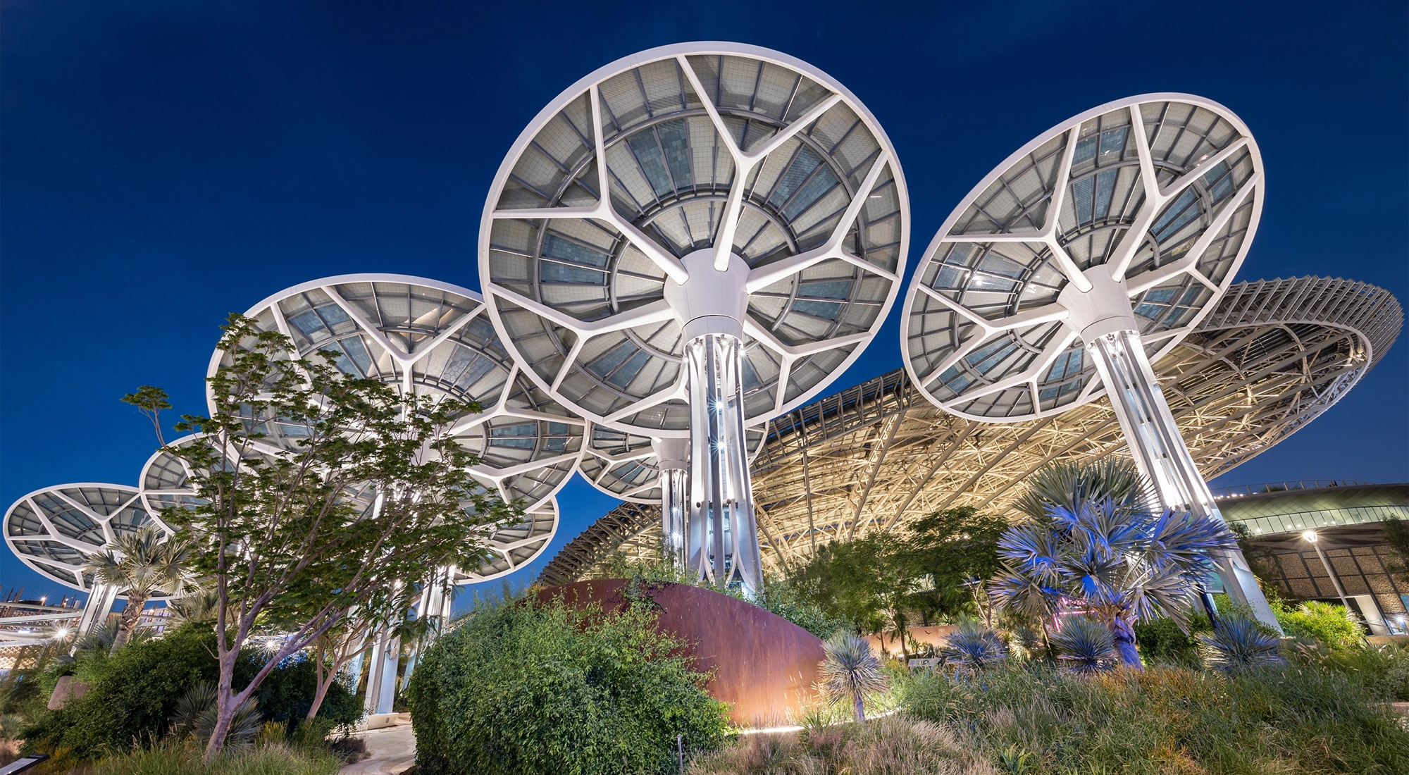 Multiple mushroom shaped solar panels against dark blue sky