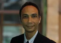 Portrait of Dargo Fitz Dinata, Director, Cost Management, Indonesia, outside in front of a blurred brown background featuring a building and mix of natural and urban elements.
