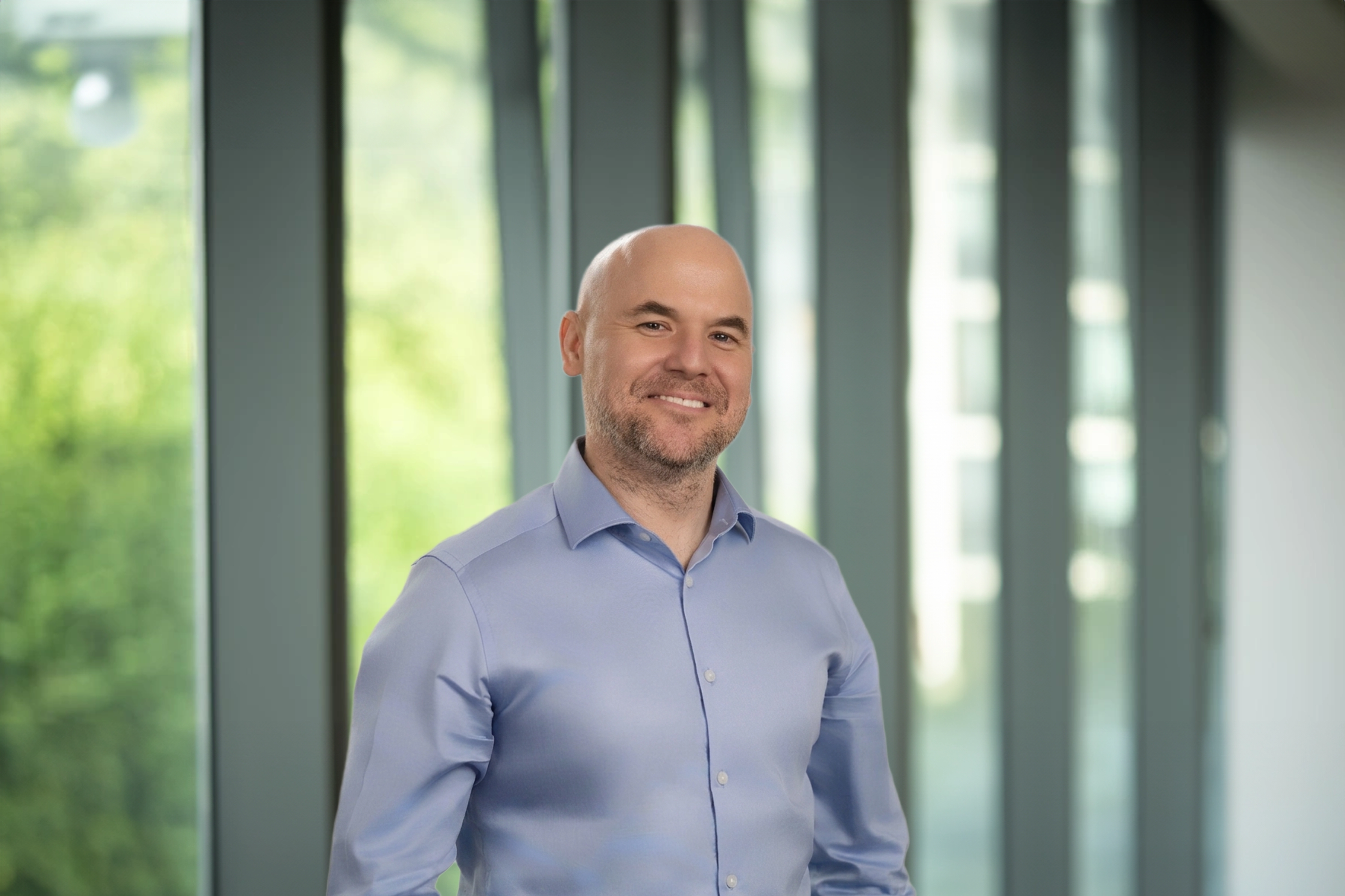 Robert McGill in modern office, with glass panels, and a softly blurred workspace behind.