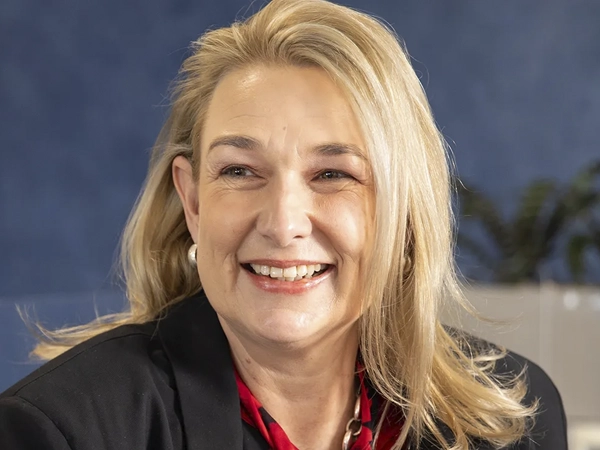 Merita Wickens, Project Director, in an office against a blue background with plants