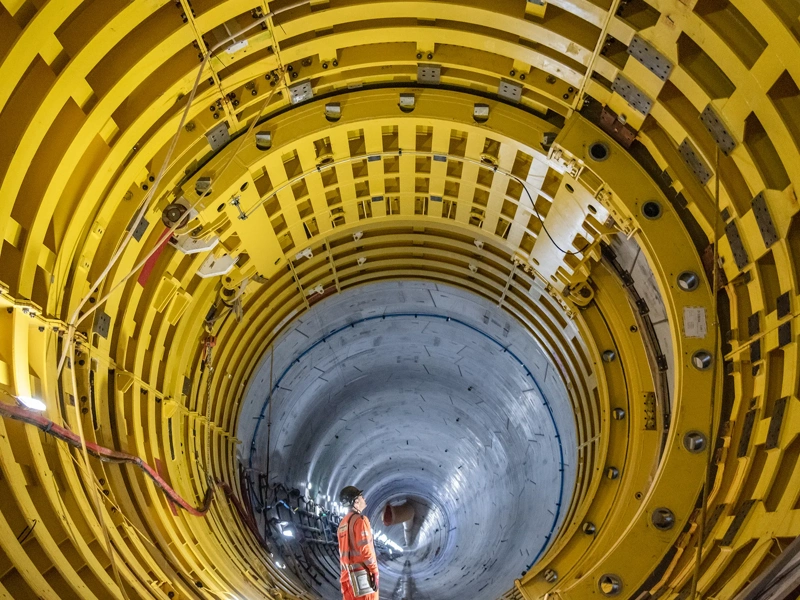 Worker in orange overalls inspects interior of a large reactor cooling system tunnel at Hinkley Point C, Somerset, UK