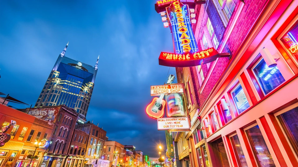 Low shot view of city with pink and orange neon lights on building.