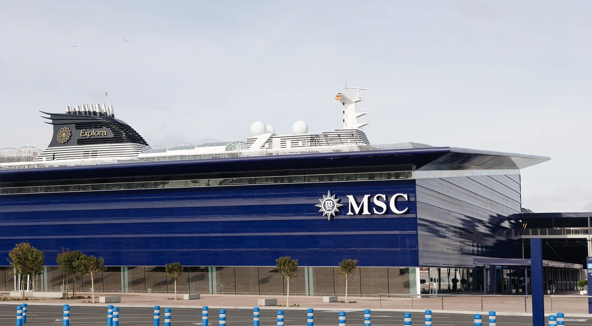 Modern blue MSC building with a large overhanging roof and glass fronted entrance, set in an open plaza
