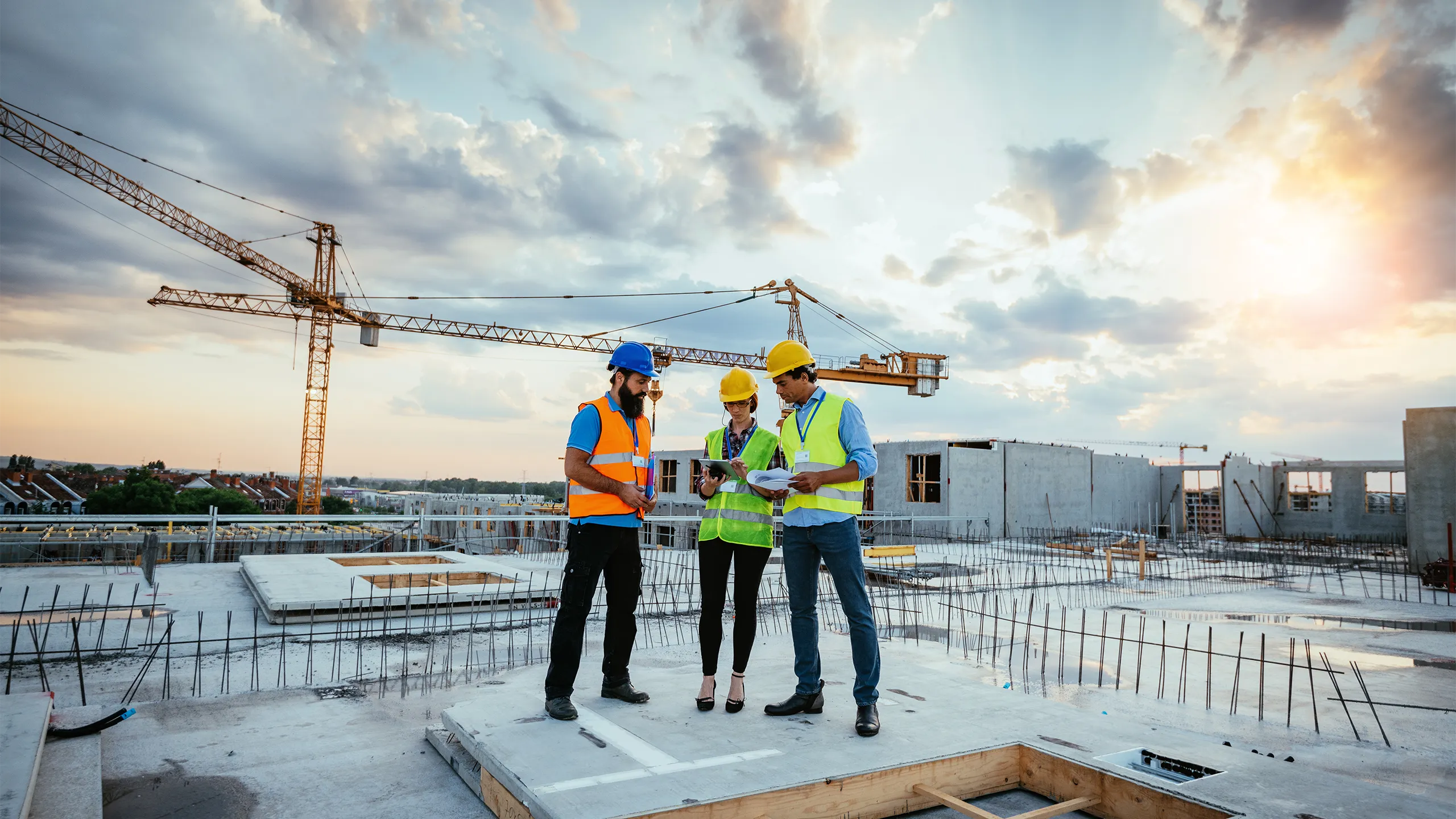 Image of Employees working on construction site, wearing protective equipment and discussing next construction phase