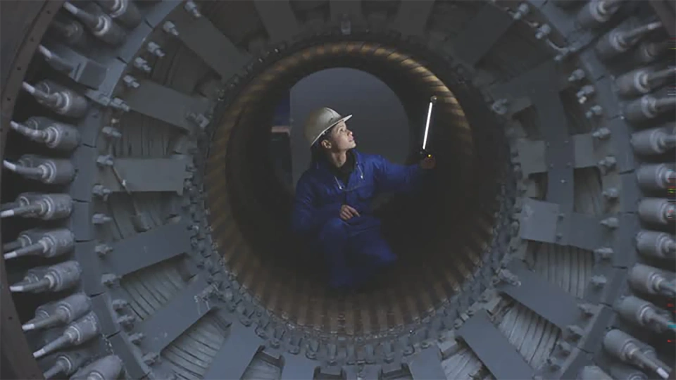 Photo of woman in blue construction wear and white helmet standing inside machine