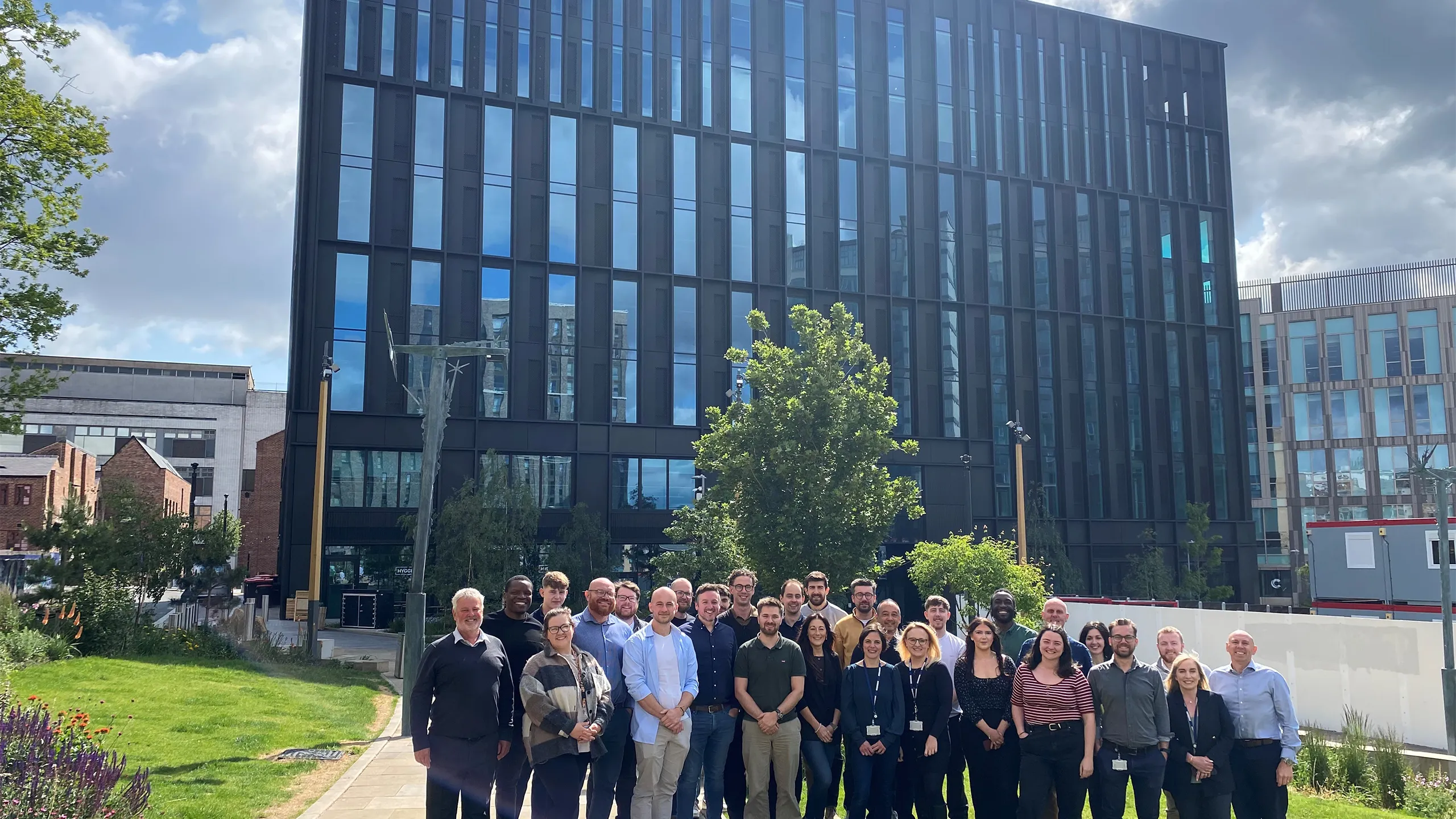 Turner and Townsend Sheffield colleagues standing outside new black window orientated office.
