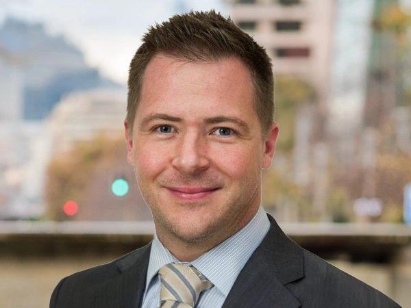 Gareth Whisson, Managing Director, Latin America, standing outside featuring an urban cityscape with tall buildings and a mix of architectural styles. The scene includes some trees with autumn foliage, adding a touch of color. 