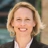 Lisa Woodruff, Executive Vice President, Global Head of Retail, outside in front of a blurred brown background featuring a building and mix of natural and urban elements.