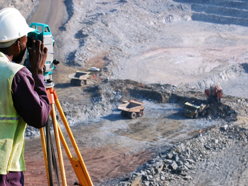 Builder looking into machine overlooking empty grovel construction site