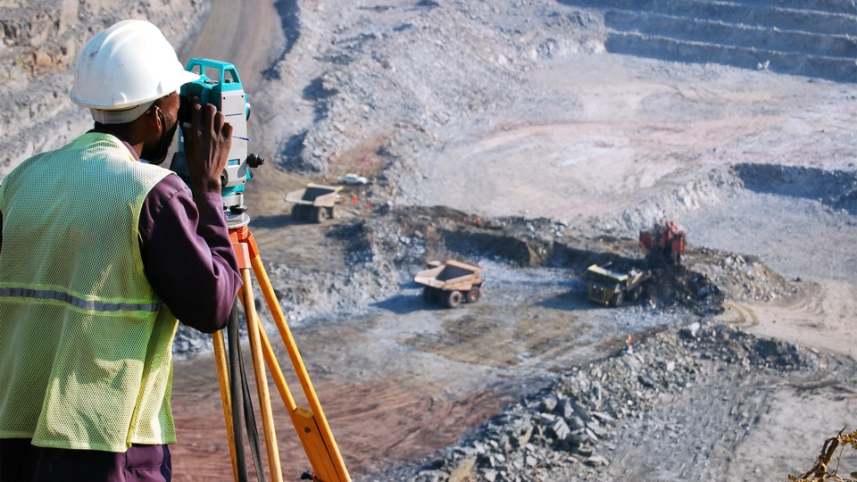 Builder looking into machine overlooking empty grovel construction site