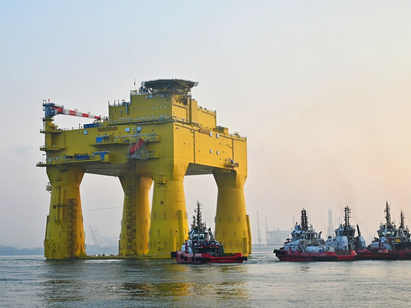 The DolWin epsilon converter station (an solid, yellow structure) floating in the sea.