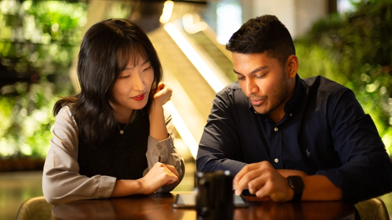 Two colleagues together looking at a tablet in a plant-filled office.