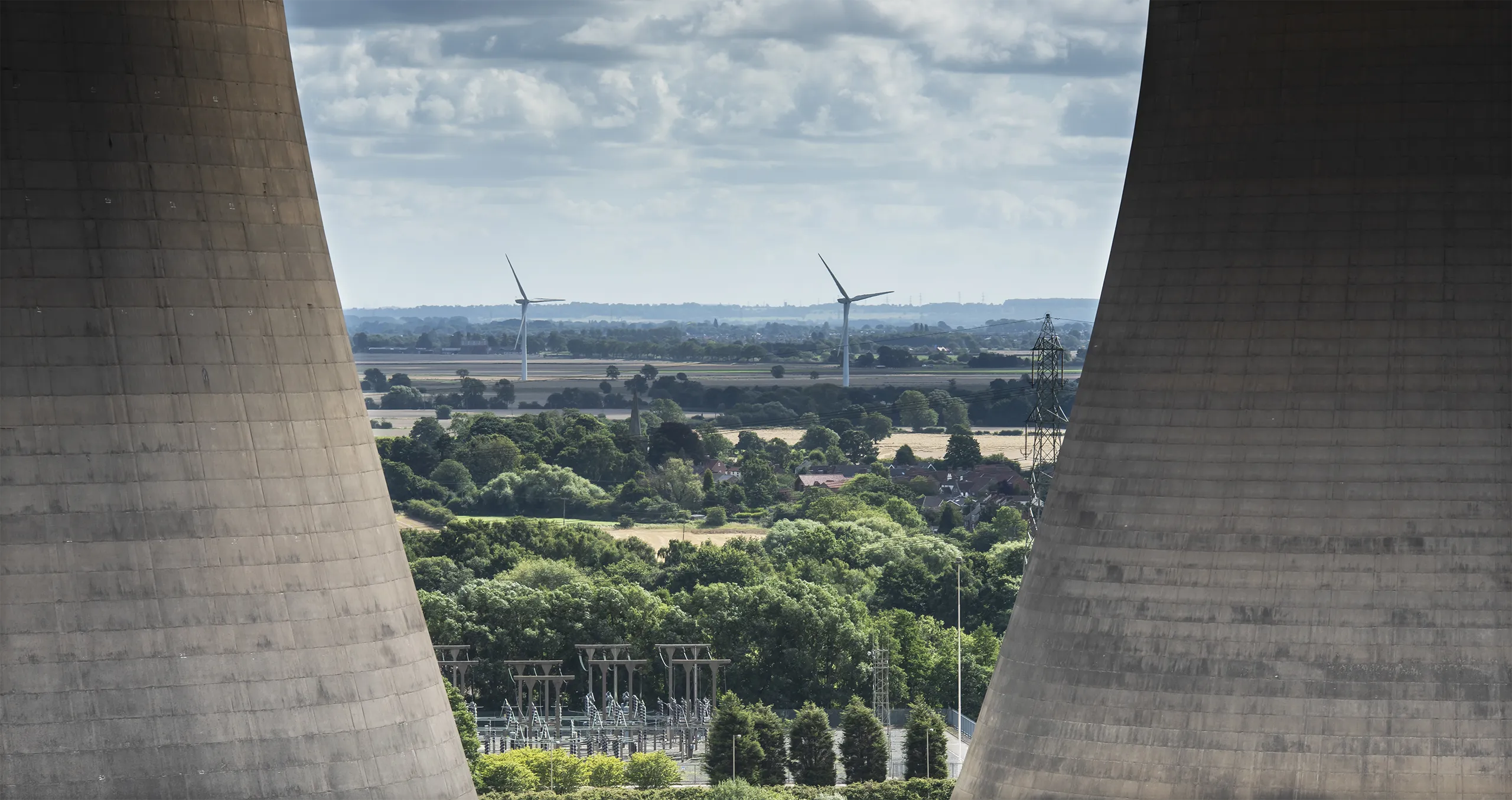 a close up view of the cooling towers at Drax power station showing a wind farm in the distance