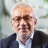 Nitesh Patel, Lead Economist, UK, standing outside in front of an outdoor urban setting, featuring modern architectural elements with clean lines. There are hints of greenery, suggesting some trees or plants.