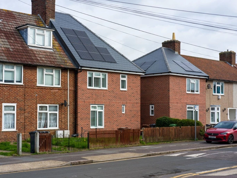 Brown houses on street with two houses that have solar panels on roof