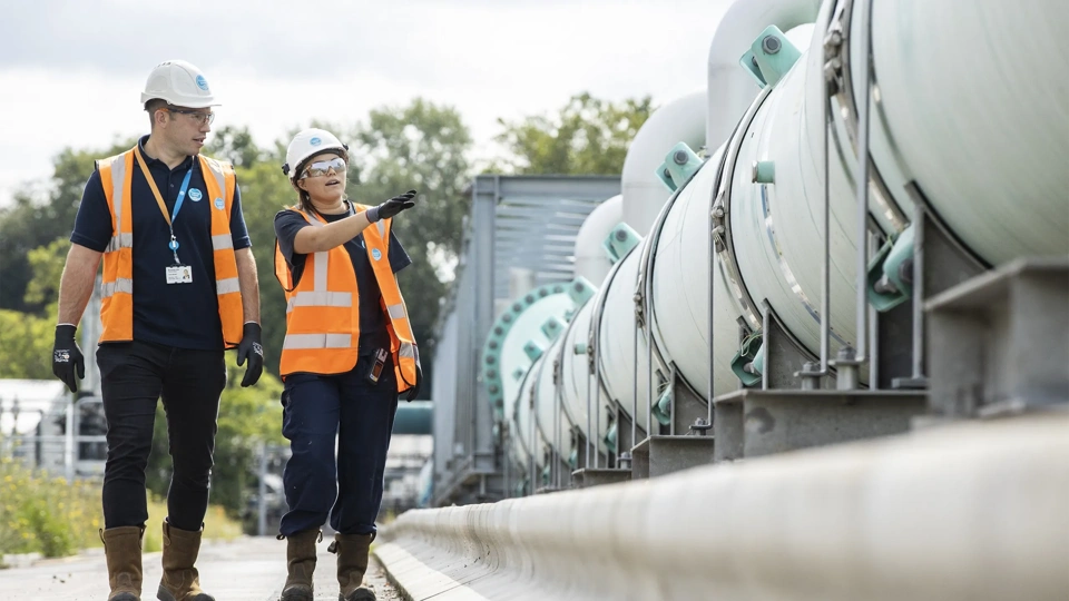 Smiling contractors walking along rows of concrete mixer trucks and planning working day at construction site