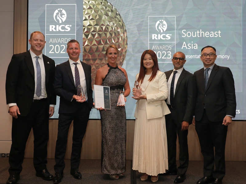 Photo of a group of six people at an awards event with two holding trophies
