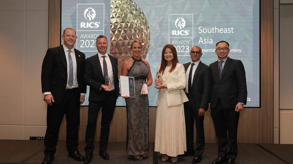 Photo of a group of six people at an awards event with two holding trophies